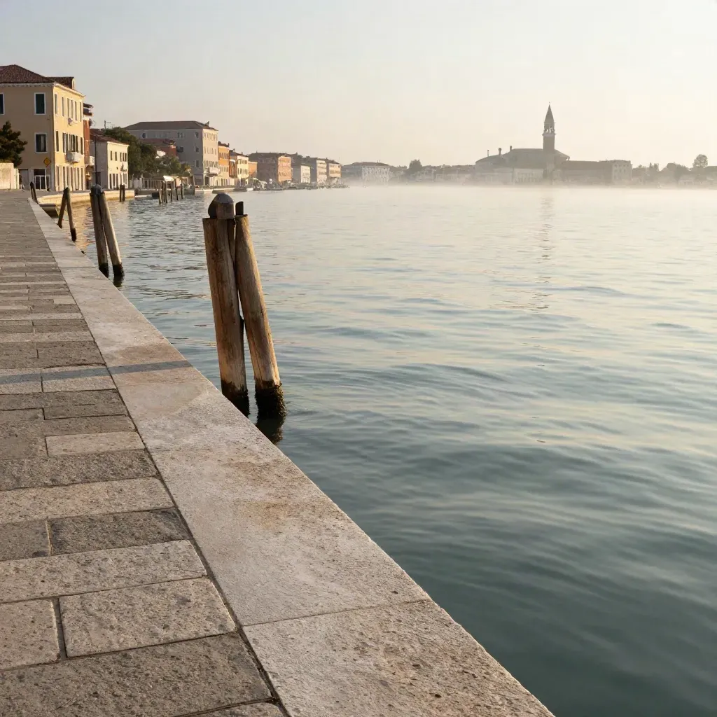 Molo in pietra chiara nella laguna veneziana all’alba, acqua calma e foschia marina.